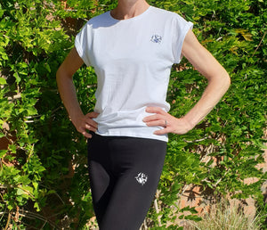 Lady standing with white t-shirt with cuffed sleeves with The Cally Collection logo in black in the top left hand corner.    The lady is also wearing black leggings with the Cally Collection logo in white at the top of the left leg.