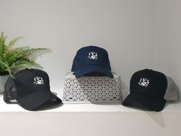 Photograph of three snapback trucker's cap from The Cally Collection in black, black/grey and navy. All with The Cally Collection logo in white.