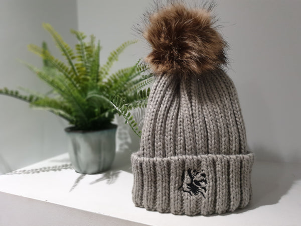 Light grey chunky beanie from The Cally Collection with removable brown faux fur bobble.    The Cally Collection logo is in black in the centre of the front fold.