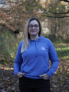 Photo of lady wearing a light blue hoody with The Cally Collection logo in white in the top left corner.