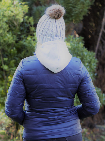 Photo of back of lady wearing a light grey hoody with a navy lightweight jacket both from The Cally Collection.  The lady is also wearing a light grey chunky beanie with a pom pom on the top from The Cally Collection.