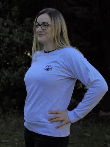 Photo of lady wearing a light grey sweatshirt with The Cally Collection logo in black in the top left corner.