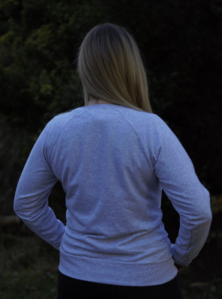 Photo of back of lady wearing a light grey sweatshirt from The Cally Collection.