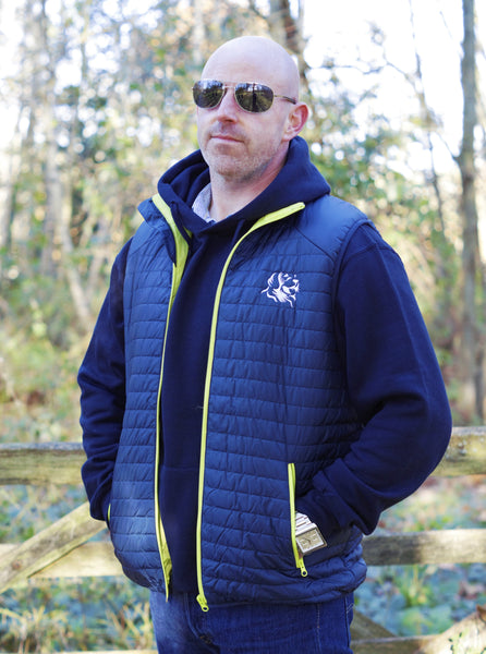 Photo of man wearing a navy hoody from The Cally Collection, with a navy gilet with lime trim and The Cally Collection logo in white in the top left corner.