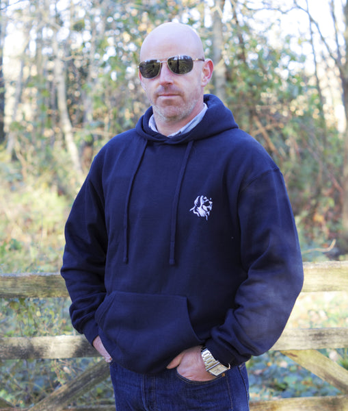 Photo of man wearing a navy hoody with The Cally Collection logo in white in the top left corner.