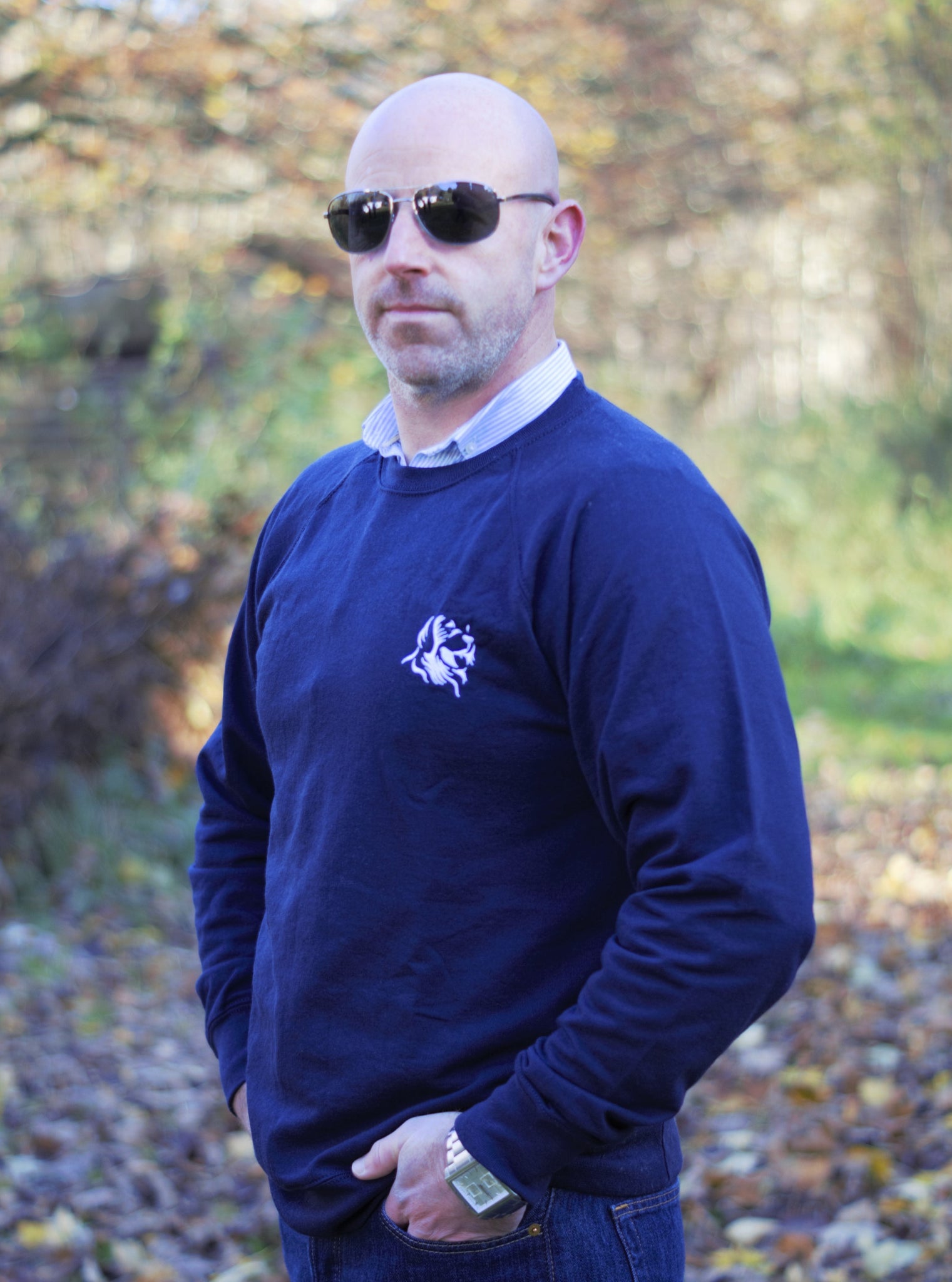 Photo of man wearing a navy sweatshirt with The Cally Collection logo in white in the top left corner.