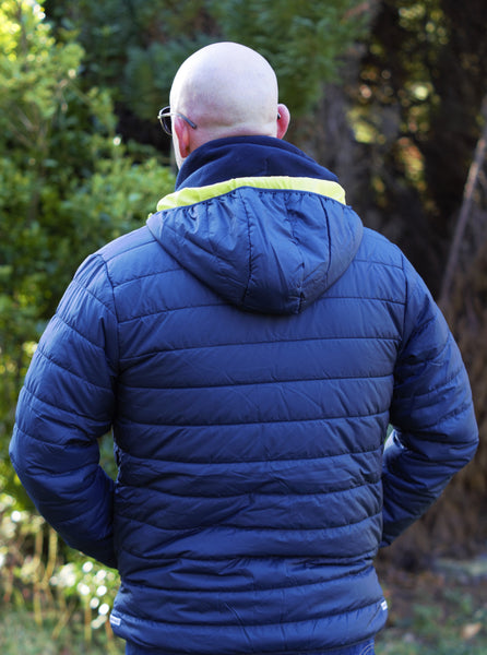 Photo of back of man wearing a navy lightweight jacket with lime trim from The Cally Collection.