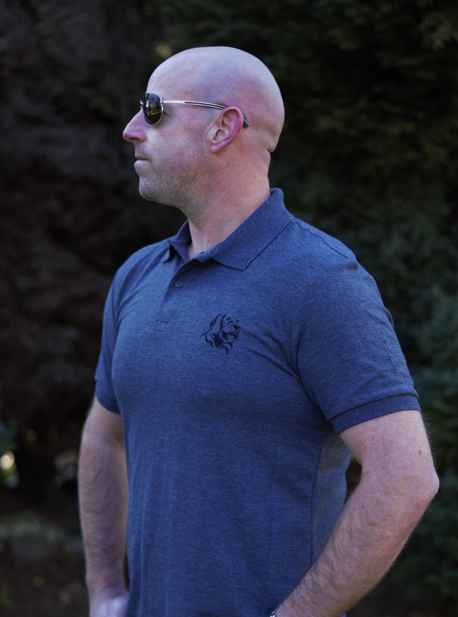 Photo of man wearing dark grey polo shirt with The Cally Collection logo in black in the top left corner.