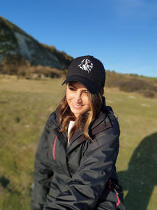 Photo of lady wearing a black trucker's cap with The Cally Collection logo in white on the front panel. 