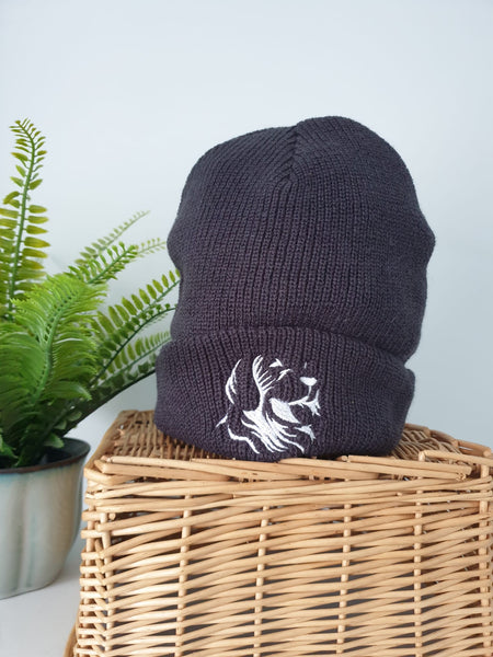 Photo of a dark grey beanie with The Cally Collection logo in white on the front. 