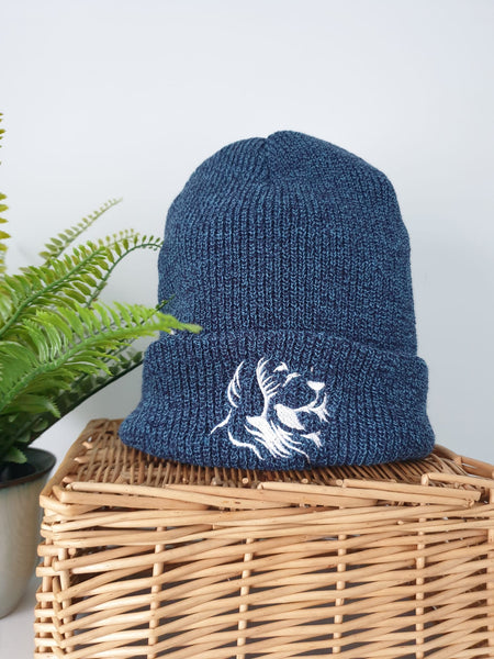 Photo of a beanie, which is a speckled blue colour, with The Cally Collection logo in white on the front. 